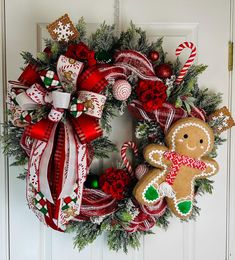 a wreath decorated with gingerbreads, candy canes and christmas decorations is hanging on the front door