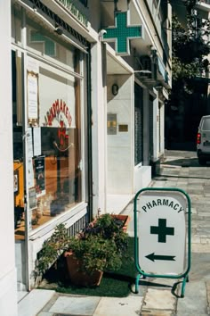 a pharmacy sign sitting on the side of a road next to a store front window