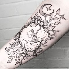 a woman's arm with flowers and a crescent on it