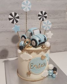 a birthday cake decorated with an old fashioned car and umbrellas for the first year