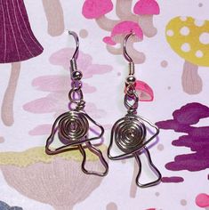 pair of silver earrings with spiral design on them sitting on a pink flowered surface