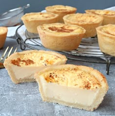 several small pies on a cooling rack with forks and spoons next to them