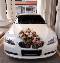 a white car decorated with flowers and greenery in front of a building on the street