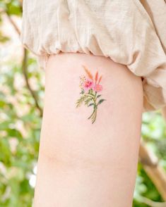 a small flower tattoo on the right side of the arm, with pink flowers in it