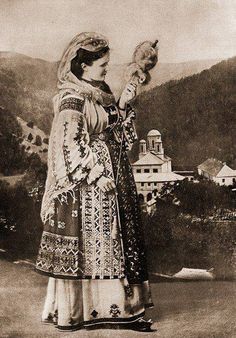 an old black and white photo of a woman holding a bird in her hand with mountains in the background