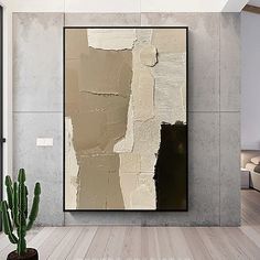 an abstract painting hangs on the wall next to a cactus in a modern living room