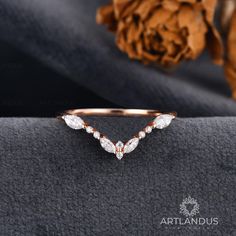 an elegant diamond ring sits on top of a piece of cloth with a flower in the background