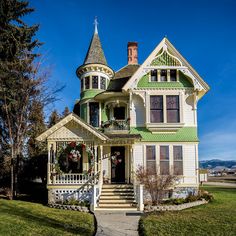 a green and white victorian style house on a sunny day