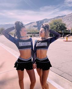 two young women standing next to each other wearing cheerleader outfits and holding hands behind their backs