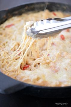 a spoon is being used to mix up some food in a skillet with cheese