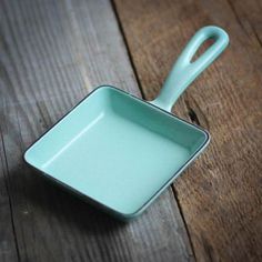 a small square dish with a spoon in it on a wooden table next to a knife