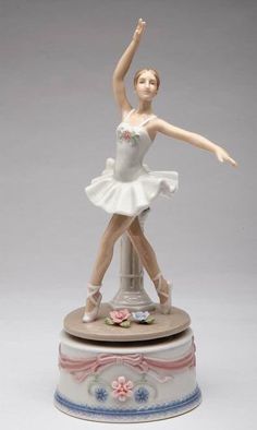 a figurine of a ballerina on top of a pedestal with her arms in the air