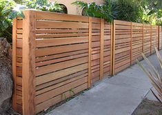 a wooden fence that is next to a tree and some plants on top of it