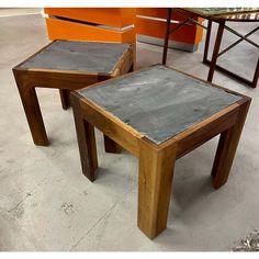 two tables made out of wood and cement sitting on concrete floor next to each other