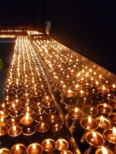 rows of lit candles sitting on top of a table