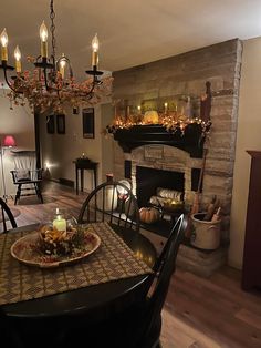 the dining room table is set for two with candles on it and plates in front of the fire place