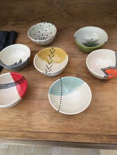 several bowls with designs on them sitting on a wooden counter top next to an oven mitt