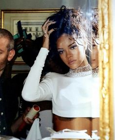 a man standing next to a woman in front of a mirror with her hand on her head