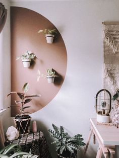 a living room with potted plants on the wall and a round mirror above it