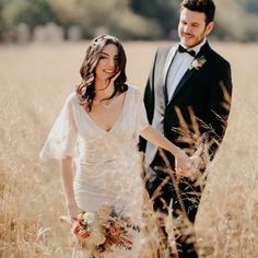 a bride and groom holding hands in the middle of an open field with tall grass