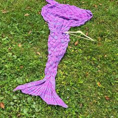 a purple knitted mermaid tail laying on the grass