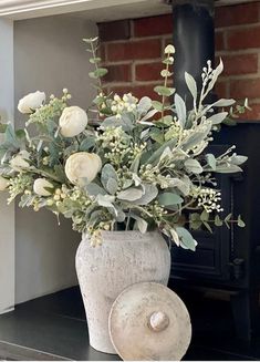 a vase filled with flowers sitting on top of a table next to a fire place