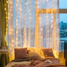 a bedroom with lights on the curtains and a bed in front of a large window