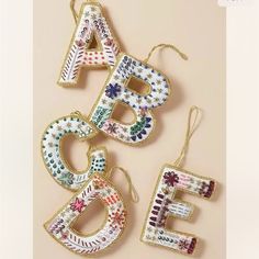 three ornaments are hanging on the wall next to each other, one is decorated with letters and flowers