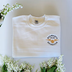 a white t - shirt sitting on top of a table next to flowers