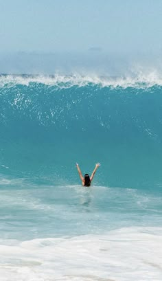 a woman is swimming in the ocean with her arms up