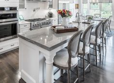 a kitchen with white cabinets and an island in front of the stove, oven and microwave