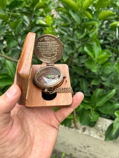 a hand holding a wooden object with a compass on it