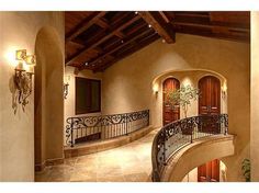 a staircase leading to the upper level of a house with wood and wrought iron railings