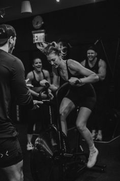 a group of people in a gym doing exercise on stationary bikes with one person holding the handlebars