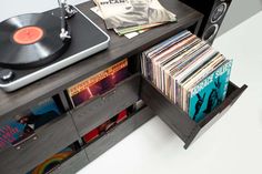 a record player is sitting next to a shelf full of cds and vinyl records on it