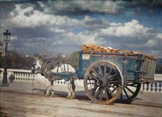 a horse drawn carriage on the side of a road with clouds in the sky behind it