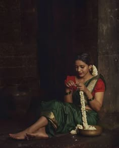 a woman sitting on the ground with a flower in her hand