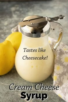 there is a cream cheese syrup in a glass pitcher with two lemons next to it