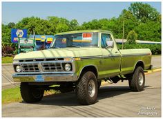 an old pick up truck is parked on the side of the road in front of a gas station