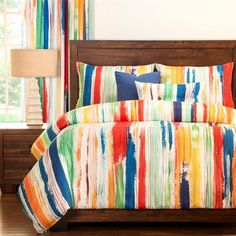 a bed with multi colored sheets and pillows