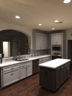 a large kitchen with white cabinets and wood floors