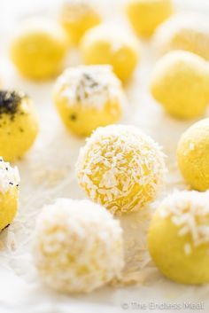 some yellow and white desserts are sitting on the table together, with black sprinkles all over them