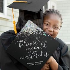 a girl in graduation cap and gown hugging her friend