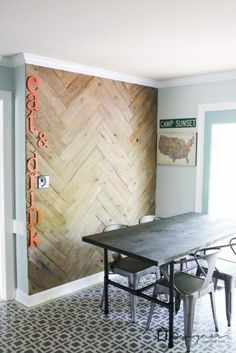 a dining room table and chairs in front of a wall with wood planks on it