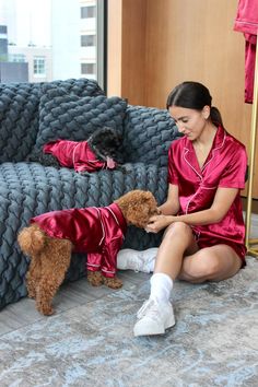 a woman sitting on the floor petting a dog wearing pajamas and socks with her legs crossed