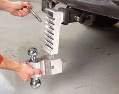 a man is working on a car's front wheel with a wrench and spanner