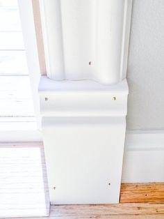 the corner of a room with a white door and wood flooring next to it