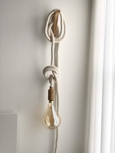 a light bulb hanging from the side of a wall next to a lamp on a rope