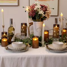 the table is set with candles, dishes and flowers in vases on top of it