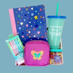 a pink lunch box filled with items like a cup, pencils, and notebook